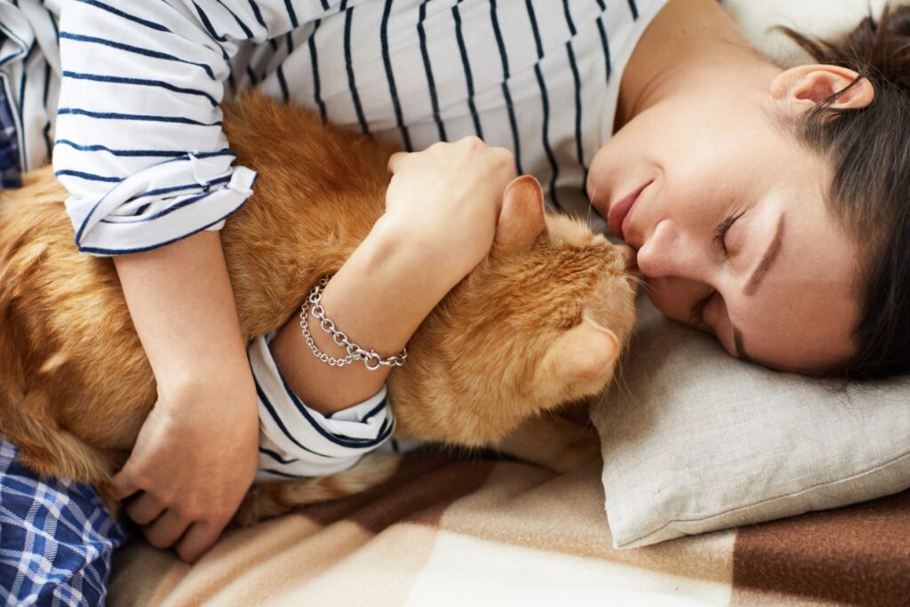 Photo shows a woman cuddling her ginger cat, caring for an elderly cat and thinking about their final years can be hard - reach out for help if you need it!